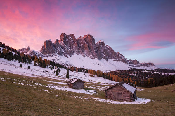 Sunrise with two wooden lodges and Odle Dolomites. Malga Gampen, Funes, Bolzano, Trentino Alto Adige - Sudtirol, Italy, Europe.