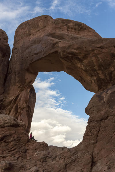 Person under Double Arch. Arches National Park, Moab, Grand County, Utah, USA.