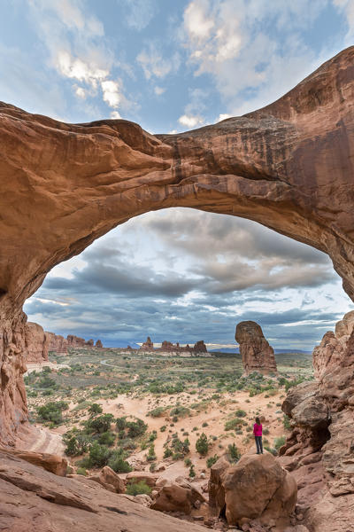Person overlooking the landscape under Double Arch. Arches National Park, Moab, Grand County, Utah, USA.