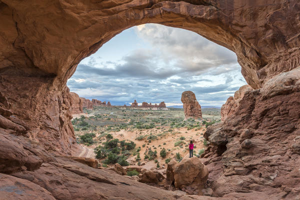 Person overlooking the landscape under Double Arch. Arches National Park, Moab, Grand County, Utah, USA.