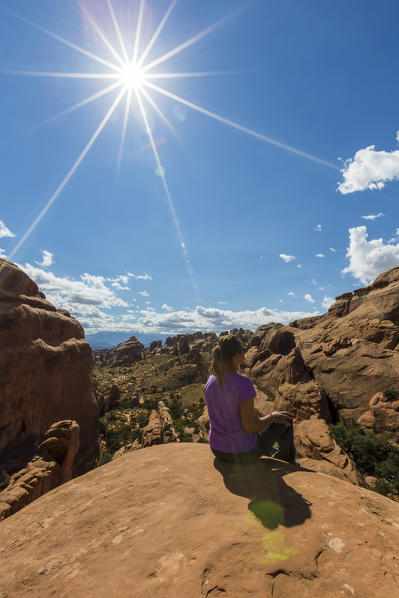 Girl overlooking the landscape on Devil's Garden trailhead. Arches National Park, Moab, Grand County, Utah, USA.
