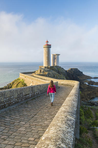 Woman walking towards Petit Minou lightouse. Plouzané, Finistère, Brittany, France.
