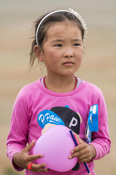 Portrait of a little girl with a pink balloon in hands. South Gobi Province, Mongolia.