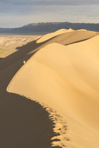 Woman walking on Khongor sand dunes in Gobi Gurvan Saikhan National Park. Sevrei district, South Gobi province, Mongolia.