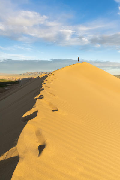 Man walking on Khongor sand dunes in Gobi Gurvan Saikhan National Park. Sevrei district, South Gobi province, Mongolia.