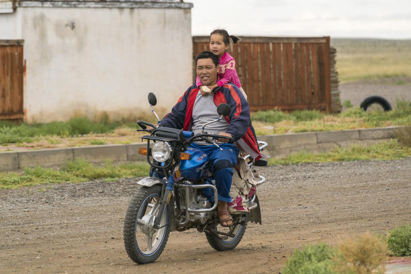 Mongolian father and daughter riding a motorbike. Huzirt, South Hangay province, Mongolia.
