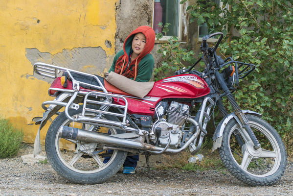 Mongolian boy with hood and motorbike. Huzirt, South Hangay province, Mongolia.