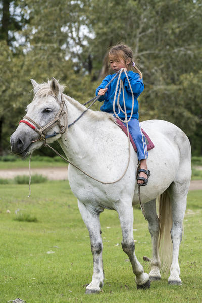 Mongolian nomadic little girl riding a horse. Hovsgol province, Mongolia.