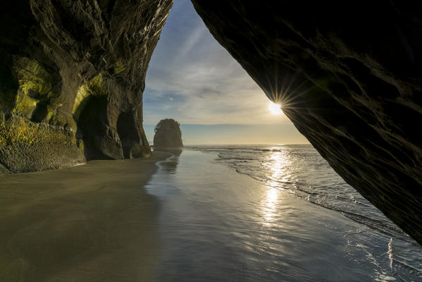 Rock cave and Elephant Rock in the background. Tongaporutu, New Plymouth district. Taranaki region, North Island, New Zealand.