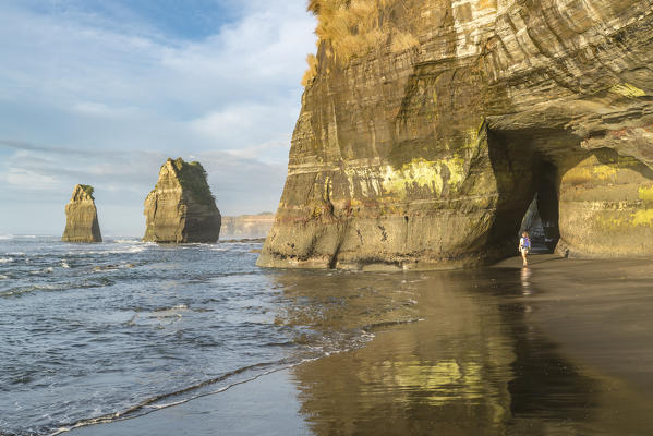 Woman walking on the beach at the Three Sisters. Tongaporutu, New Plymouth district. Taranaki region, North Island, New Zealand. (MR)