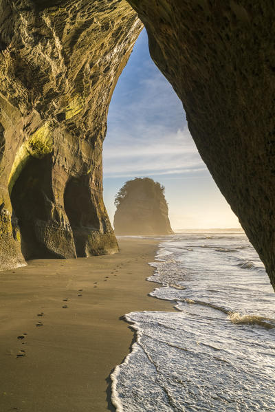 Rock cave and Elephant Rock in the background. Tongaporutu, New Plymouth district. Taranaki region, North Island, New Zealand.