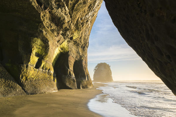 Rock cave and Elephant Rock in the background. Tongaporutu, New Plymouth district. Taranaki region, North Island, New Zealand.