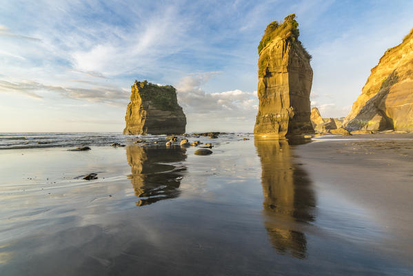 Golden light over the Three Sisters and Elephant Rock. Tongaporutu, New Plymouth district. Taranaki region, North Island, New Zealand.