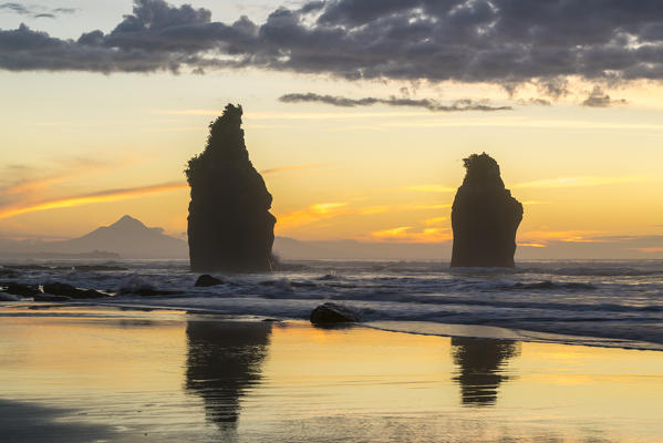 Sunset at the Three Sisters, with Mount Taranaki in the background. Tongaporutu, New Plymouth district. Taranaki region, North Island, New Zealand.