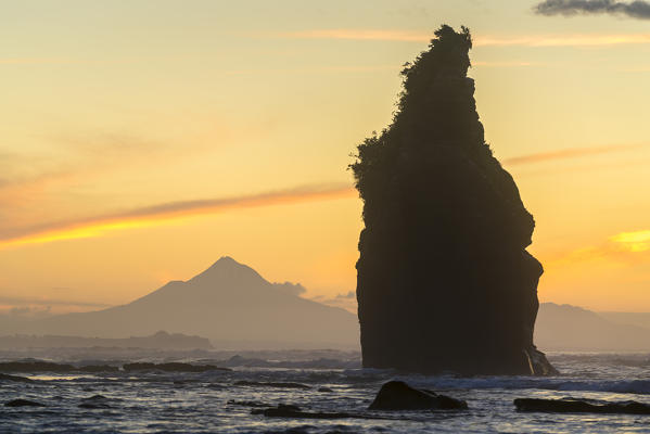 Sunset at the Three Sisters, with Mount Taranaki in the background. Tongaporutu, New Plymouth district. Taranaki region, North Island, New Zealand.