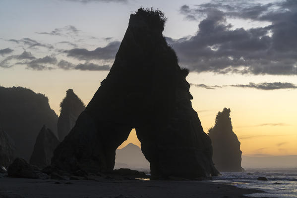 Mount Taranaki seen through a rock cave at the Three Sisters beach. Tongaporutu, New Plymouth district. Taranaki region, North Island, New Zealand.