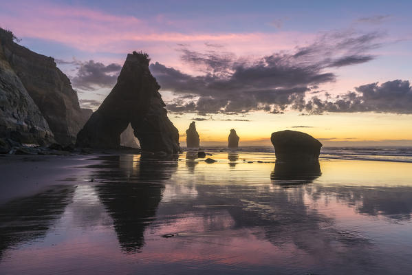 Rock reflect with low tide at the Three Sisters beach, at sunset. Tongaporutu, New Plymouth district. Taranaki region, North Island, New Zealand.
