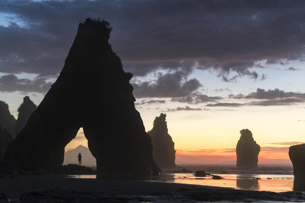 Woman's silhouette at the Three Sisters beach, with Mt Taranaki seen behind her.  Tongaporutu, New Plymouth district. Taranaki region, North Island, New Zealand. (MR)