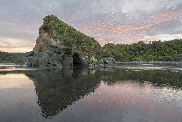 Reflection of a caved rock with low tide at the Three Sisters beach. Tongaporutu, New Plymouth district. Taranaki region, North Island, New Zealand.