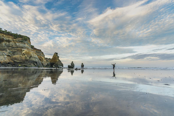 Man walking on the Three Sisters beach. Tongaporutu, New Plymouth district. Taranaki region, North Island, New Zealand.