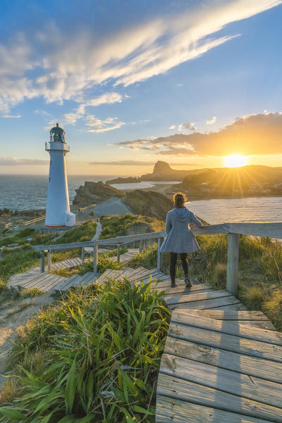 Woman descending the steps to Castlepoint lighthouse at sunset. Castlepoint, Wairarapa region, North Island, New Zealand. (MR)