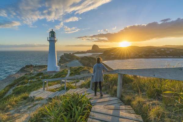 Woman descending the steps to Castlepoint lighthouse at sunset. Castlepoint, Wairarapa region, North Island, New Zealand. (MR)