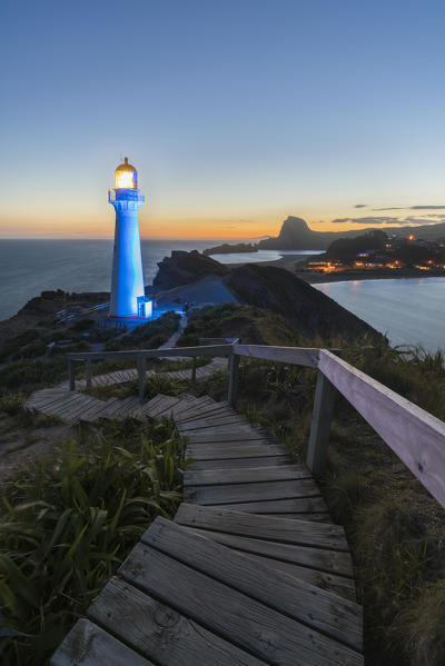 Castlepoint lighthouse lit in blue at dusk. Castlepoint, Wairarapa region, North Island, New Zealand.