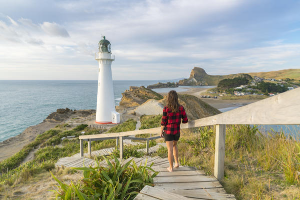 Woman descending the footpath towards Castlepoint lighthouse. Castlepoint, Wairarapa region, North Island, New Zealand.