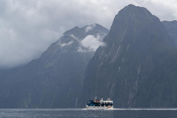 Boat and mountains in Milford Sound in summer. Fiordland NP, Southland district, Southland region, South Island, New Zealand.