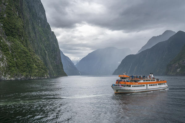 Touristic boat in Milford Sound on a cloudy summer day. Fiordland NP, Southland district, Southland region, South Island, New Zealand.