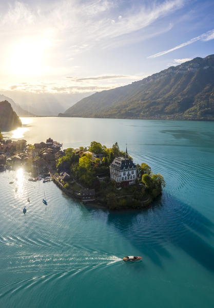 Aerial view of the village of Iseltwald and it's peninsula with the old Castle during an autumnal sunset on Lake Brienz. Iseltwald, Lake Brienz, Bernese Oberland, Interlaken-Oberhasli district, Canton of Bern, Switzerland.