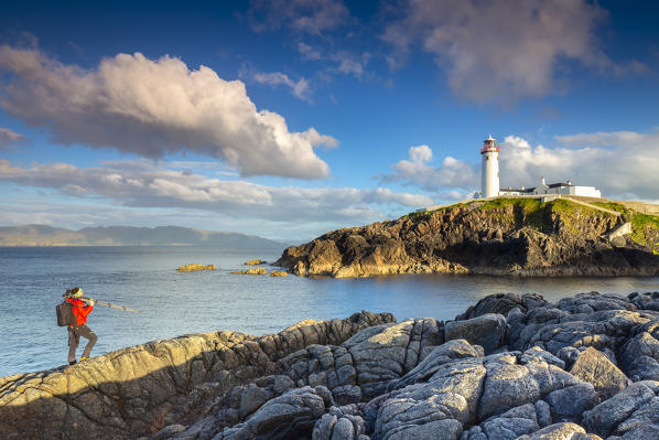 A photographer admiring the view of the Fanad Head (Fánaid) lighthouse at sunset, County Donegal, Ulster region, Ireland, Europe.