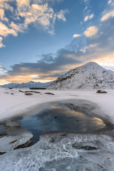 Clouds reflected in the frozen lake Montespluga, Chiavenna Valley, Sondrio province, Valtellina, Lombardy, Italy