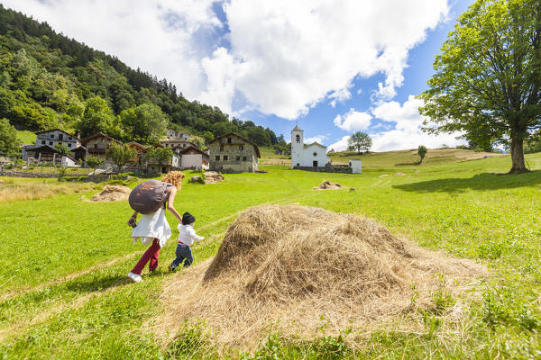 Mother and child walking in the green meadows around Daloo, Chiavenna Valley, Sondrio province, Valtellina, Lombardy, Italy