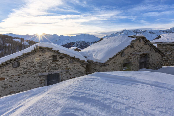 Sunburst on the snowy huts, Alpe Groppera, Madesimo, Valchiavenna, Valtellina, Sondrio province, Lombardy, Italy