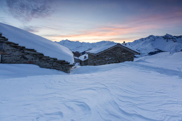Snow covered huts at sunrise, Alpe Groppera, Madesimo, Valchiavenna, Valtellina, Sondrio province, Lombardy, Italy