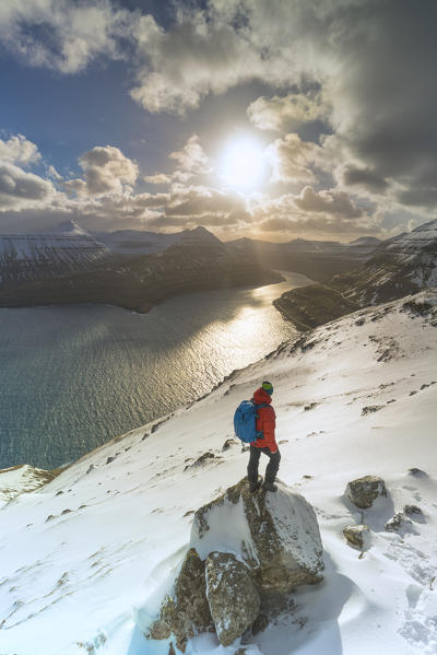 Hiker on rocks admiring Funningur fjord, Eysturoy island, Faroe Islands, Denmark (MR)