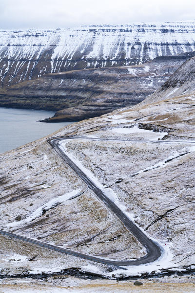 Winding road on mountains towards the ocean, Funningur, Eysturoy island, Faroe Islands, Denmark