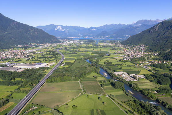 Hang gliding over green fields and villages of lower Valtellina, Sondrio province, Lombardy, Italy