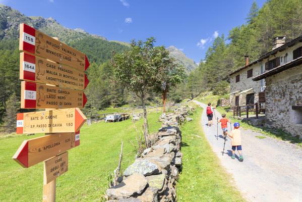 Mother and sons walk on path towards Rifugio Valmalza, Valle delle Messi, Valcamonica, province of Brescia, Lombardy, Italy