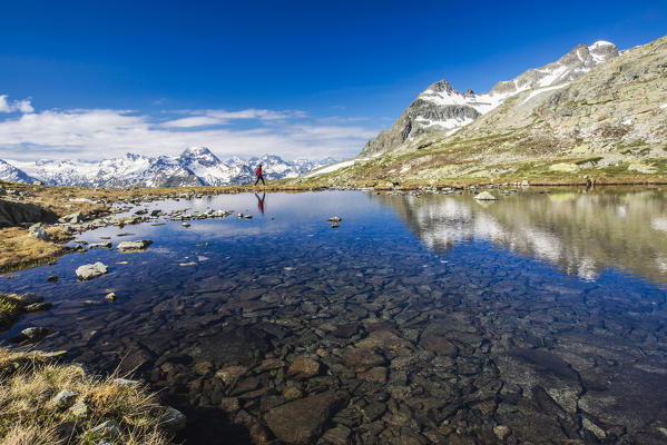 Hiker walking on the shore of Lej da la Tscheppa, St. Moritz, Engadin, canton of Graubunden, Switzerland