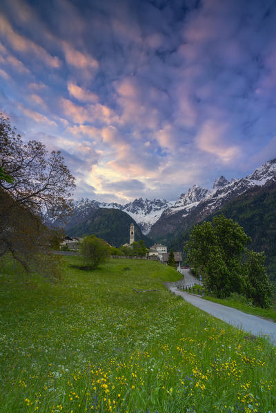 Cloudy sky at sunrise over mountains and meadows around Soglio, Bregaglia Valley, canton of Graubunden, Switzerland
