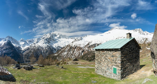 Panoramic of Monte Disgrazia covered with snow and stone huts at Alpe Oro in spring, Valmalenco, Valtellina, Lombardy, Italy