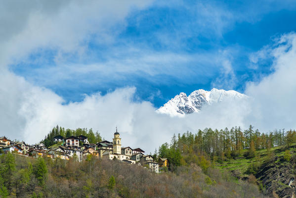 Clouds framing the alpine village of Primolo in spring, Valmalenco, Valtellina, Sondrio province, Lombardy, Italy