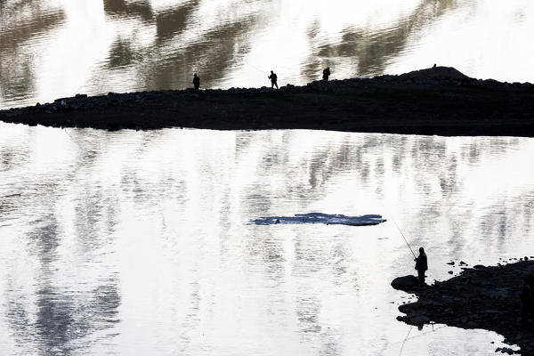 Silhouettes of fishermen at sunrise, Lake Montespluga, Valchiavenna, Sondrio province, Valtellina, Lombardy, Italy