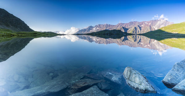 Panoramic of Cima di Pietra Rossa mirrored in clear water of Lago Nero at sunrise, Gavia Pass, Valfurva, Valtellina, Lombardy, Italy