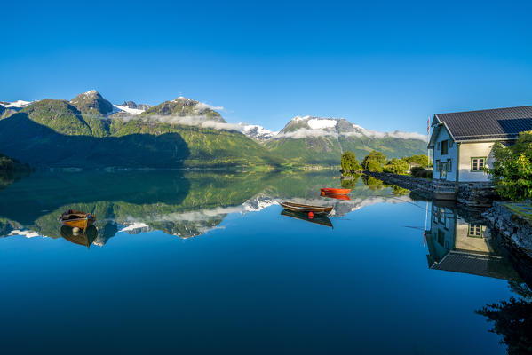 Boats moored in the blue Oppstrynsvatn Lake with the old hotel of Hjelle on shores, Oppstryn, Sogn og Fjordane county, Norway
