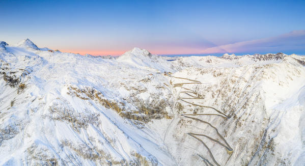 Aerial panoramic of Stelvio Pass and winding road covered with snow at dawn, Bormio, Sondrio province, Valtellina, Lombardy, Italy