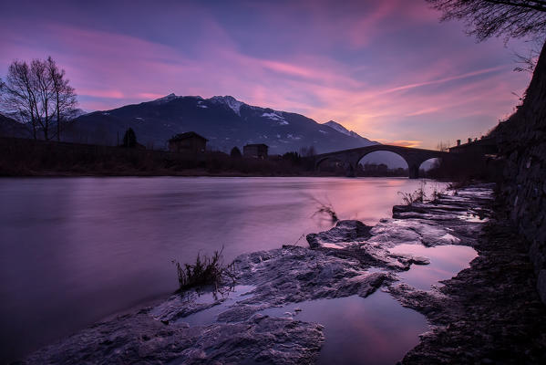 A purple sunset reflecting in the River Adda by the Ganda Bridge in Morbegno, Valtellina, Italy