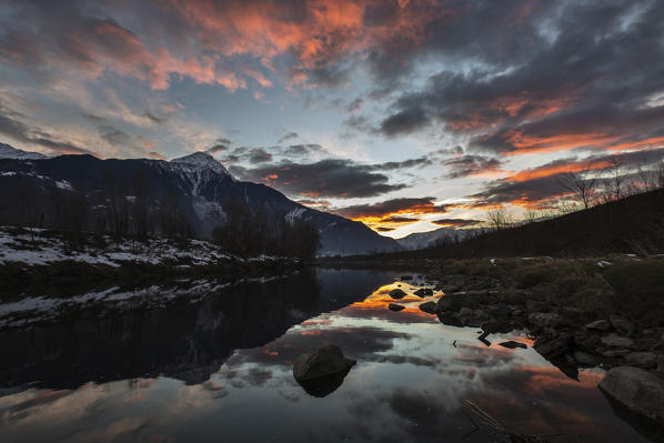 The colors of an autumnal sunset reflecting in the River Adda, Valtellina, Lombardy Italy Europe